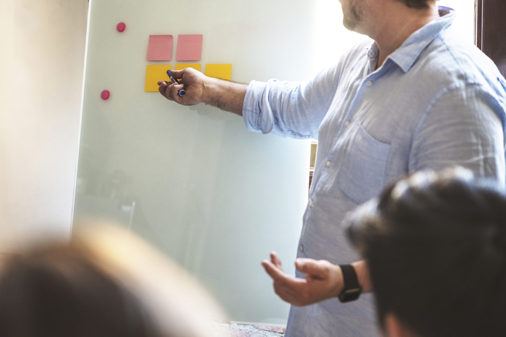 A workshop facilitator pinning notes to a glass board