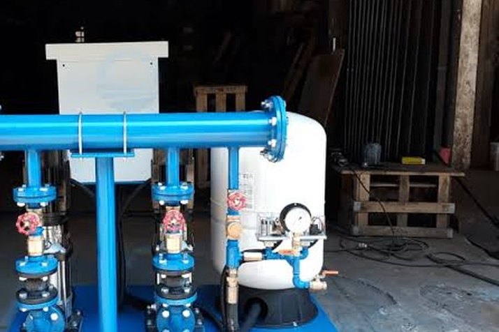 A blue booster pump set with a pressure tank in a workshop