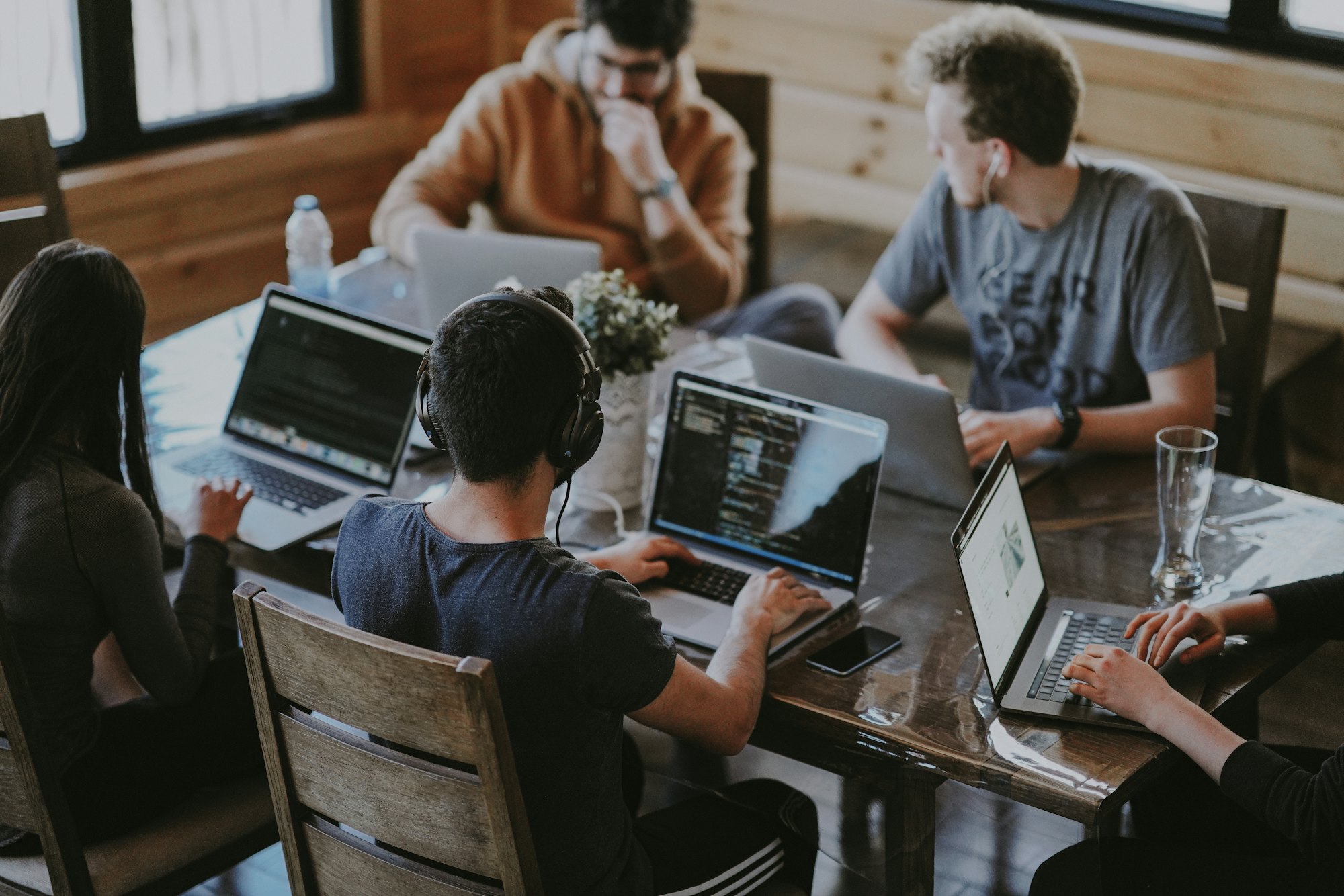 A team working across laptops around one table, seen from above